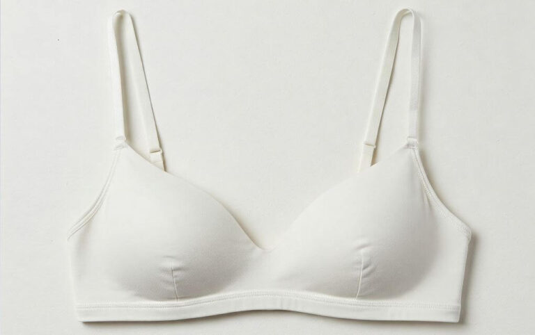 Soutien-gorge blanc grisé posé à plat, montrant des signes de ternissement.